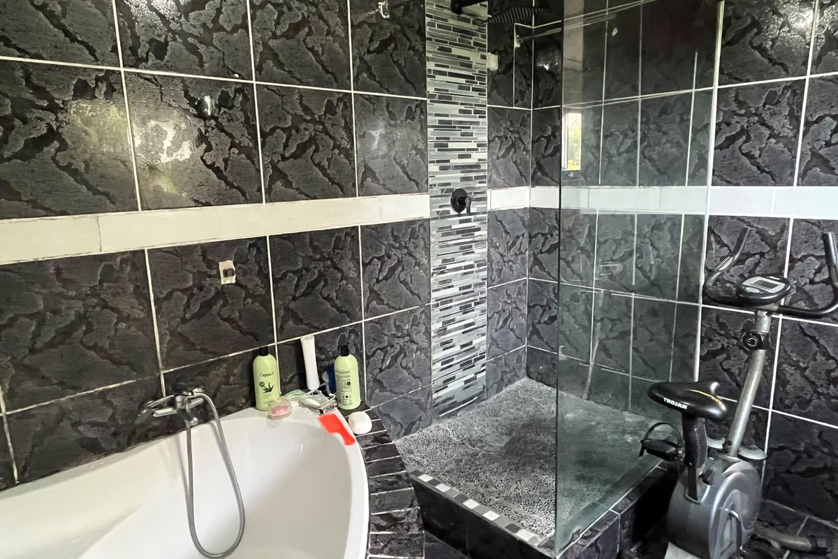 Bathroom featuring a freestanding bathtub, a walk-in shower with glass screen, and dark textured wall tiling with a decorative mosaic accent strip.