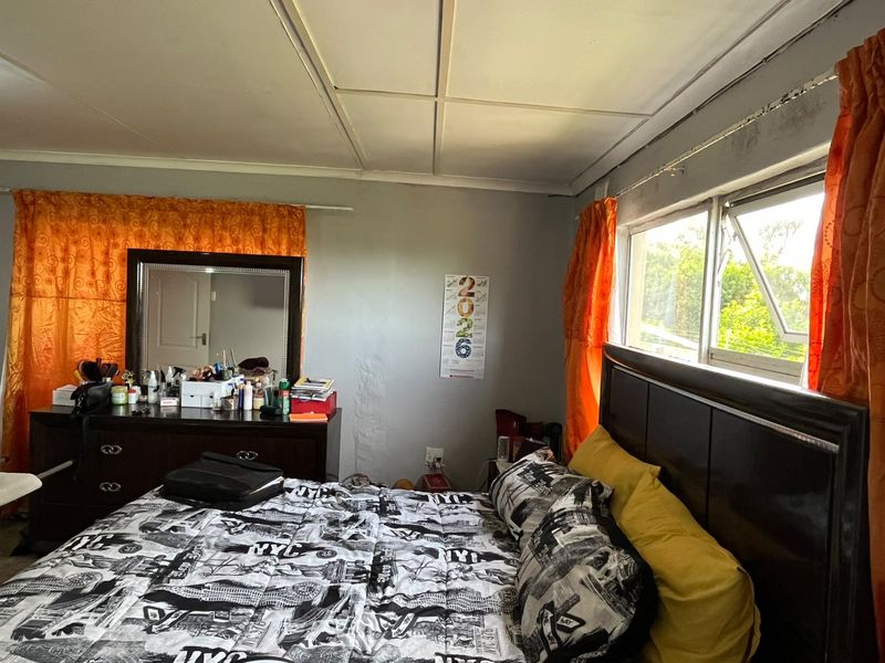 A bedroom featuring casement windows and ceiling panels, currently showing signs of wear including wall surface imperfections and ceiling joint deterioration.