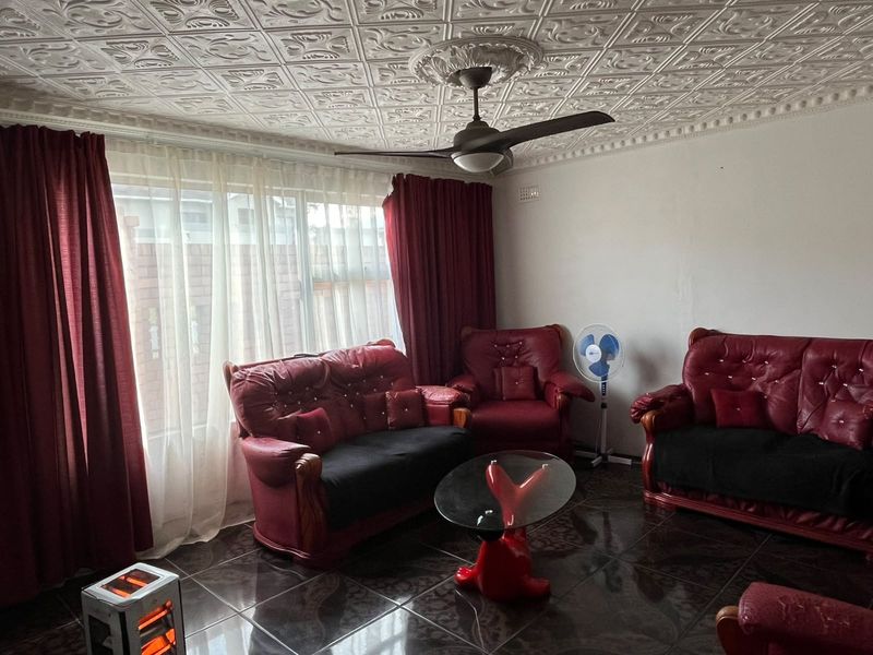 Living room featuring decorative ceiling tiles, a ceiling fan, and dark tiled flooring.