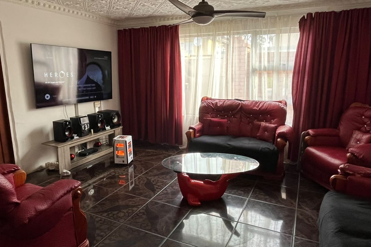 A living room featuring decorative ceiling tiles, a ceiling fan, and dark tiled flooring, providing a functional space for relaxation.