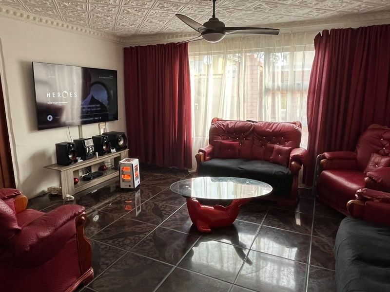 A living room featuring decorative ceiling tiles, a ceiling fan, and dark tiled flooring, providing a functional space for relaxation.