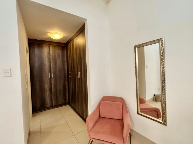 A well-maintained hallway featuring dark wood-finish built-in cupboards and neutral floor tiles, providing ample storage space.
