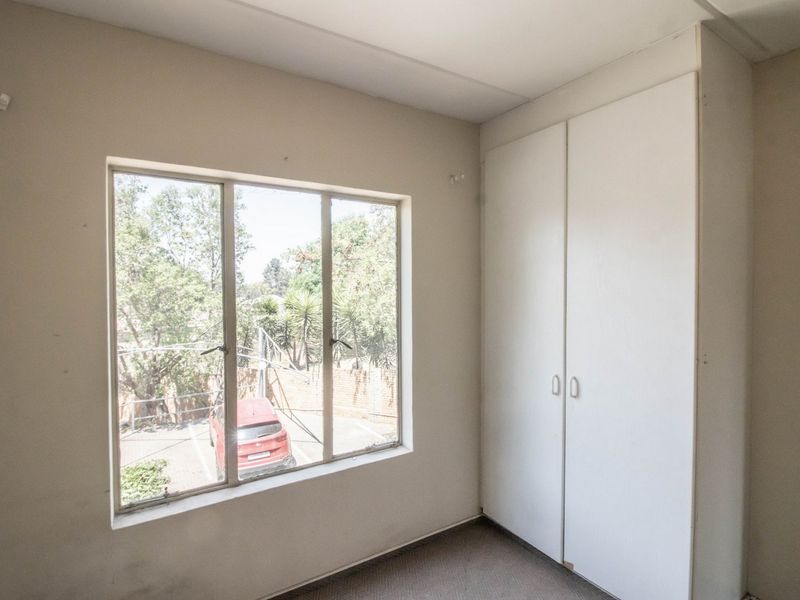A vacant bedroom featuring a built-in wardrobe and large window, offering a blank canvas for personalization.