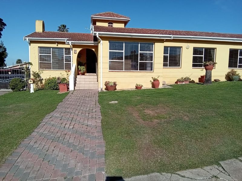 Front elevation of a single-story house featuring a tiled roof, arched entrance, and a brick paved walkway leading to the front door.