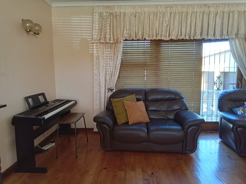 A living room featuring timber flooring and a sliding glass door with security gate, providing access to the exterior.