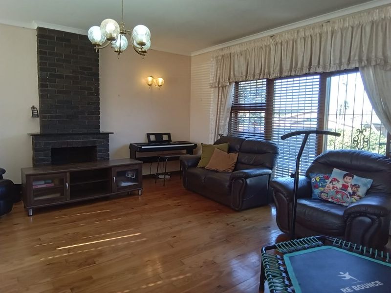 A living room featuring a dark brick fireplace, polished hardwood flooring, and a large sliding glass door with security gate access.