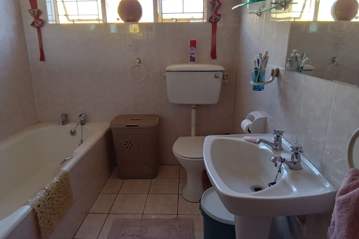A functional bathroom featuring a bathtub, pedestal basin, and toilet with neutral ceramic wall and floor tiles.
