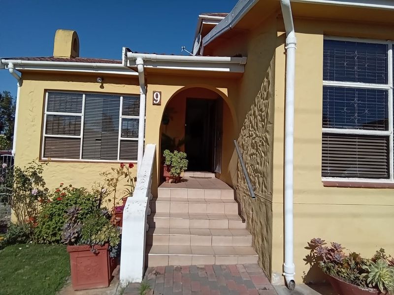 Front entrance of a residential home featuring tiled steps, an arched doorway, and security-fitted windows with a textured exterior facade.