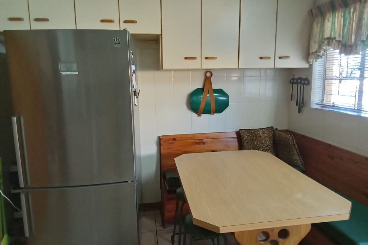 A functional kitchen area featuring built-in cabinetry, tiled backsplash, and tiled flooring, providing a practical space for meal preparation and dining.