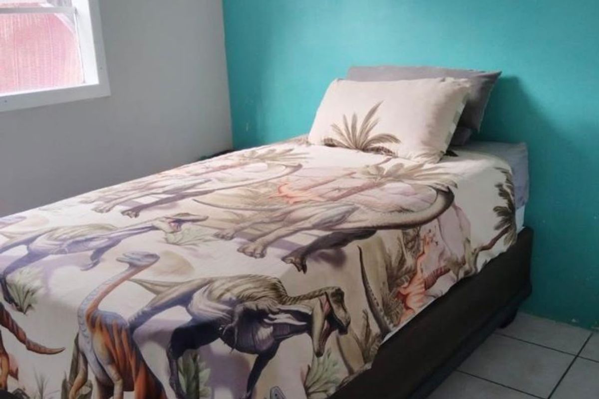 A bedroom featuring tiled flooring and a bright accent wall, providing a functional space for a child's room.