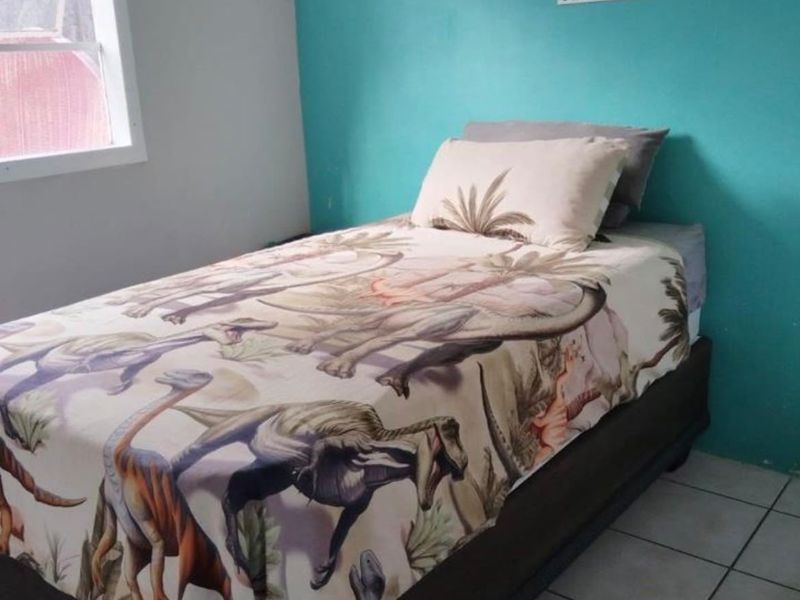 A bedroom featuring tiled flooring and a bright accent wall, providing a functional space for a child's room.