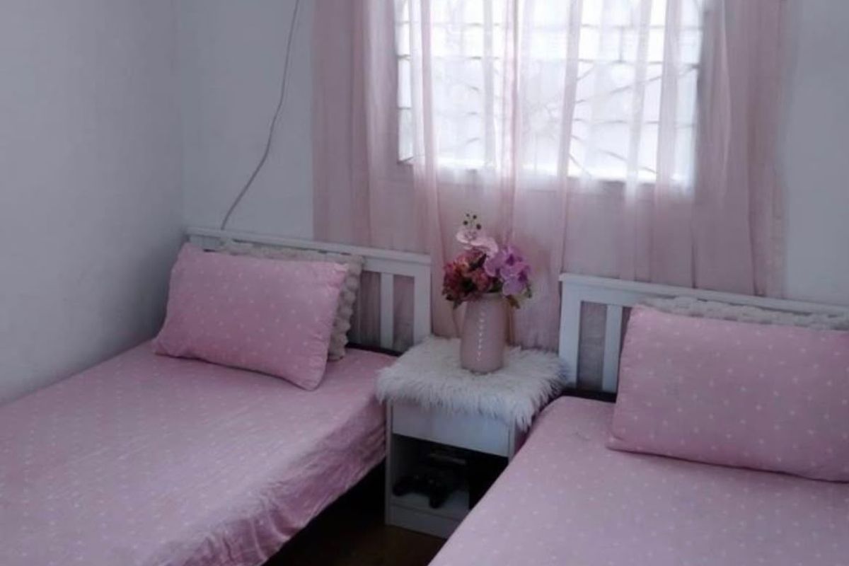 A compact bedroom featuring laminate flooring and a window fitted with security bars.