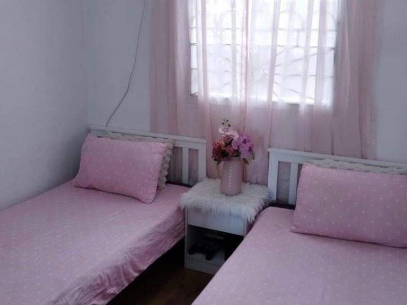 A compact bedroom featuring laminate flooring and a window fitted with security bars.