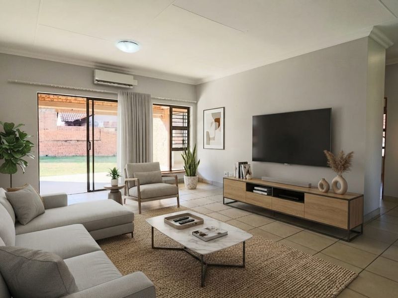 A bright and well-maintained living room featuring tiled flooring, a split-system air conditioner, and large sliding glass doors providing access to the patio.