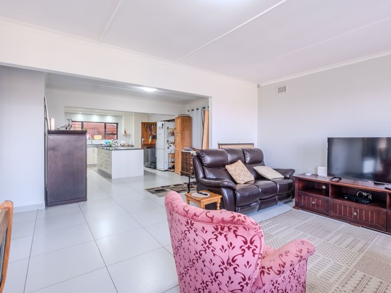 Open-plan living area featuring tiled flooring and a connected kitchen space with cabinetry and an island, offering a functional layout.