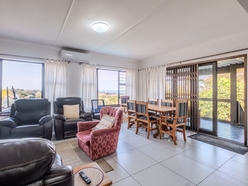 Spacious open-plan living and dining area featuring tiled floors, split-system air conditioning, and large sliding doors providing access to an outdoor patio.