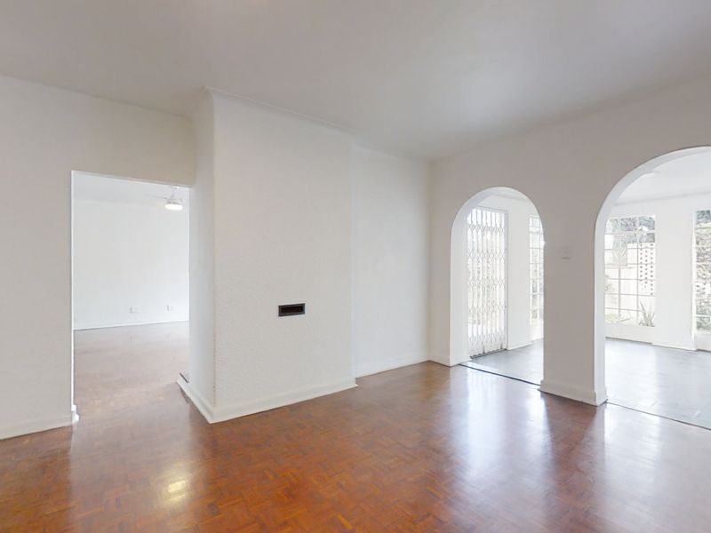 Spacious living area featuring classic parquet flooring and elegant arched doorways leading to adjacent rooms and outdoor access.