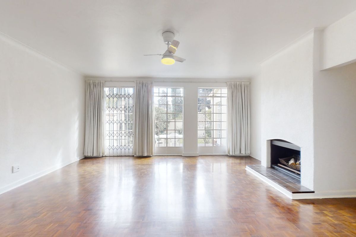 Spacious living room featuring polished parquet flooring, a built-in fireplace, and large glass doors providing natural light and access to the exterior.