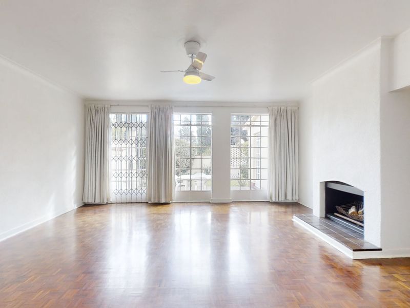 Spacious living room featuring polished parquet flooring, a built-in fireplace, and large glass doors providing natural light and access to the exterior.
