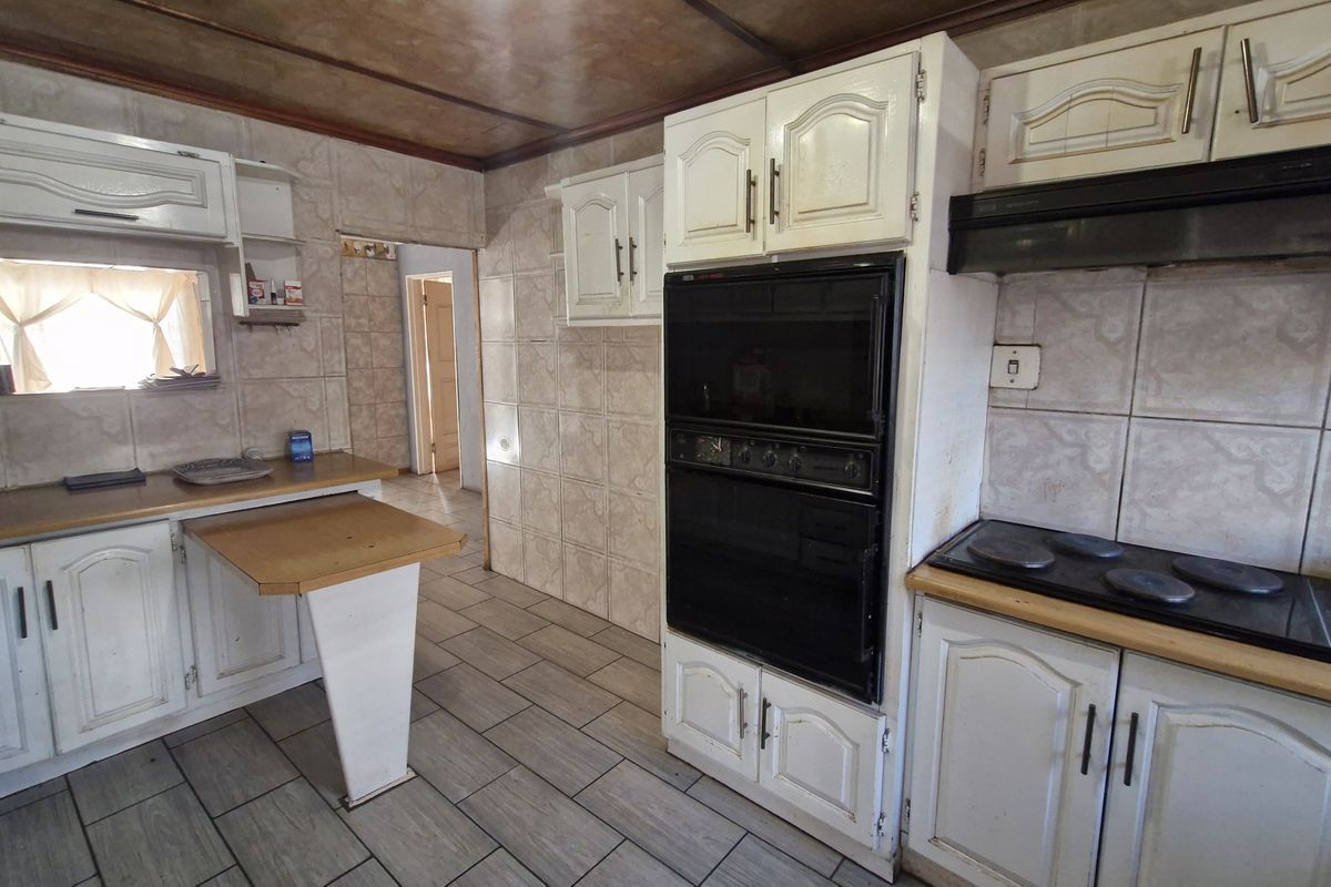 A dated kitchen featuring built-in cabinetry, tiled walls, and integrated appliances, offering a functional layout ready for modern renovation and cosmetic updates.