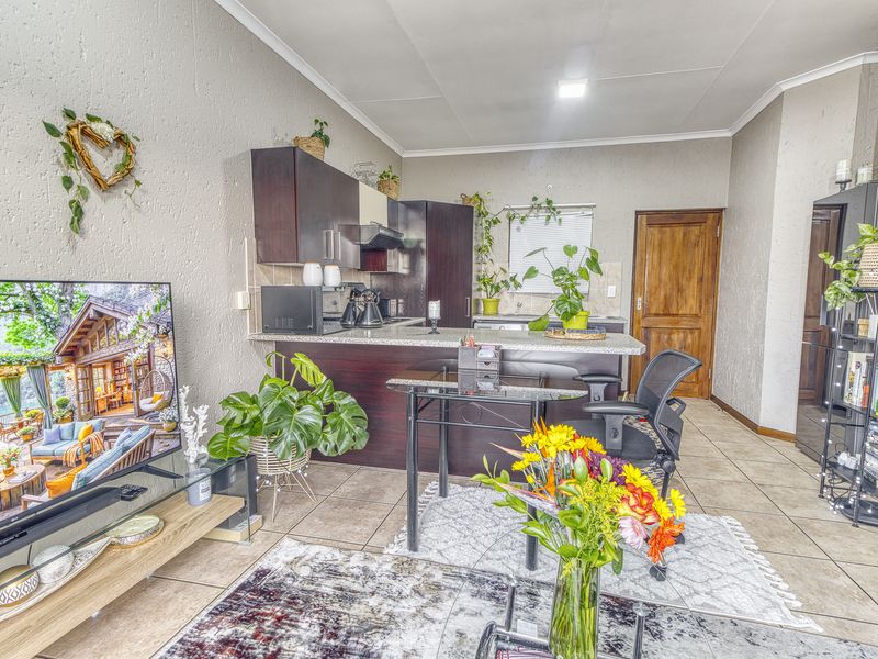 Open-plan living and kitchen area featuring dark wood cabinetry, granite countertops, and tiled flooring throughout.
