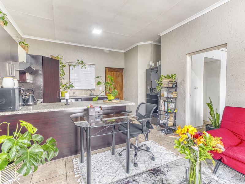 Open-plan living area featuring a kitchen with dark wood cabinetry, granite countertops, and tiled flooring, seamlessly connecting to the adjacent living space.