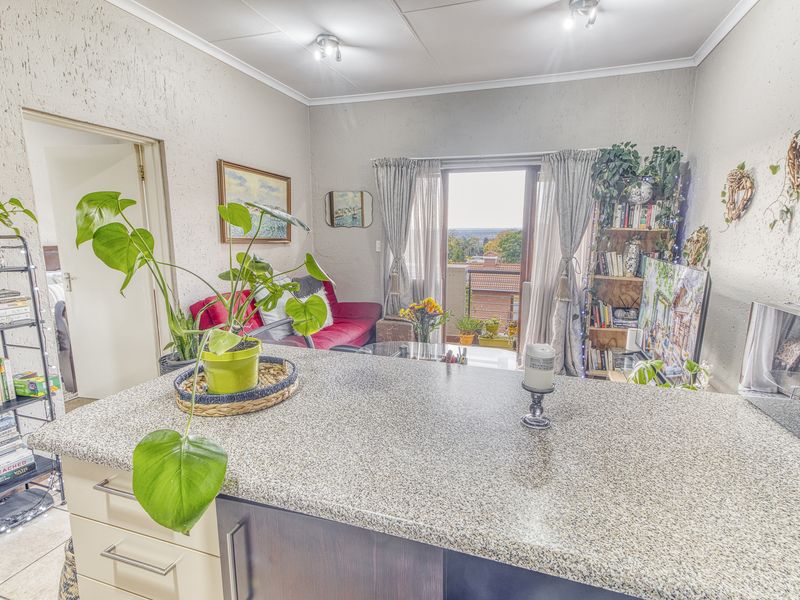 Open-plan living area featuring a granite breakfast bar, neutral finishes, and direct access to a balcony with scenic views.