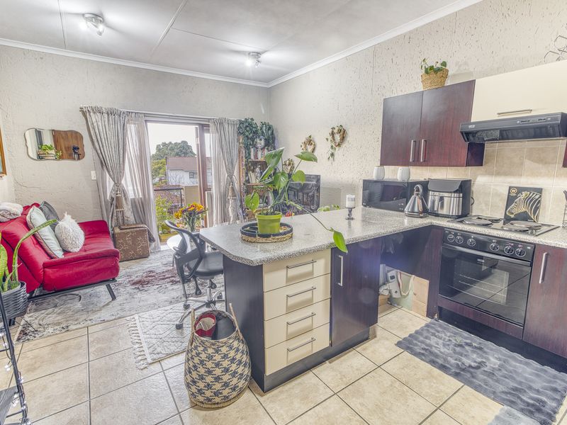 Open-plan living area featuring a functional kitchen with built-in cabinetry, granite countertops, and direct access to a balcony through sliding glass doors.