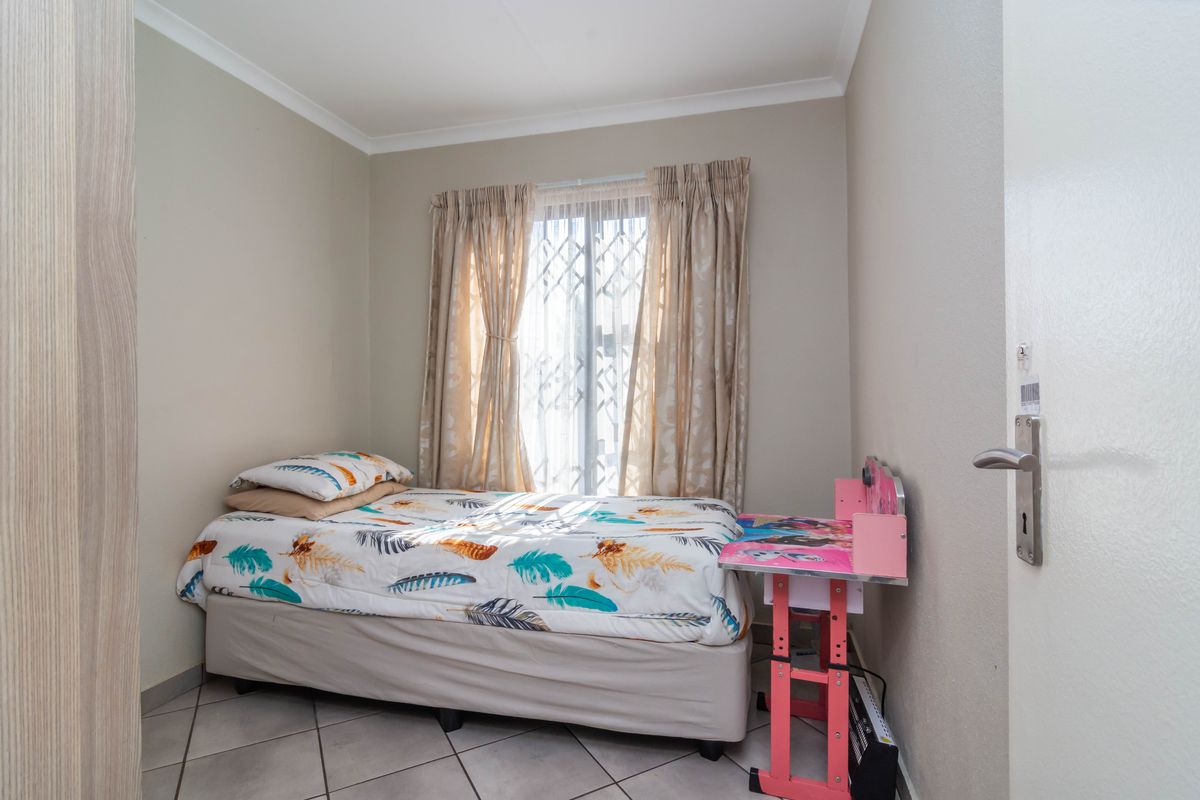 A compact bedroom featuring tiled flooring, a built-in wardrobe, and a window fitted with a security gate.