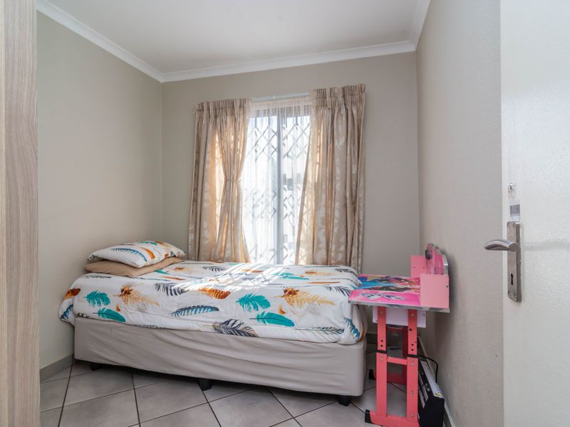 A compact bedroom featuring tiled flooring, a built-in wardrobe, and a window fitted with a security gate.