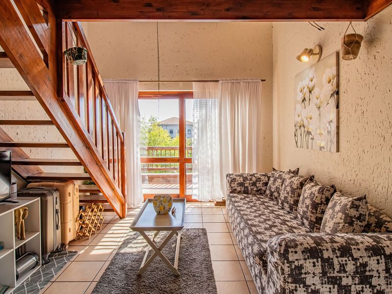 Living room featuring a wooden staircase, textured walls, tiled flooring, and a sliding glass door providing access to an outdoor balcony area.
