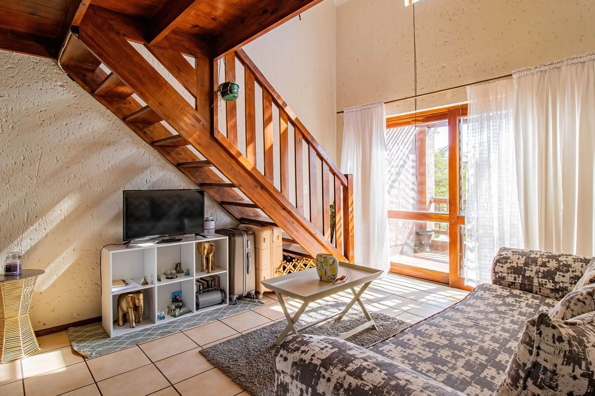A living room featuring a wooden staircase, tiled flooring, and a sliding glass door leading to an outdoor area.