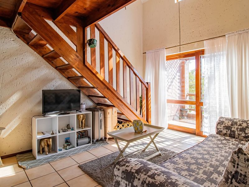 A living room featuring a wooden staircase, tiled flooring, and a sliding glass door leading to an outdoor area.