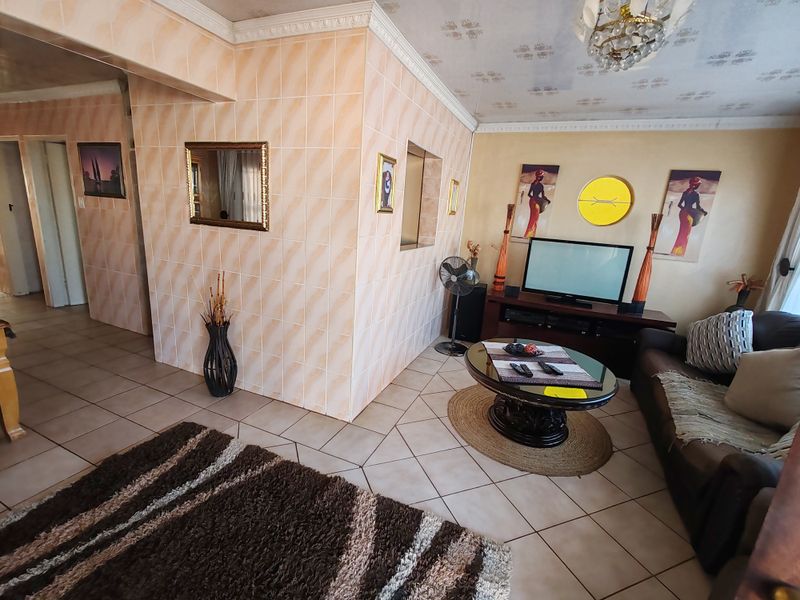 Living room featuring ceramic floor tiles, decorative ceiling cornices, and distinctive tiled wall cladding with a circular accent window.