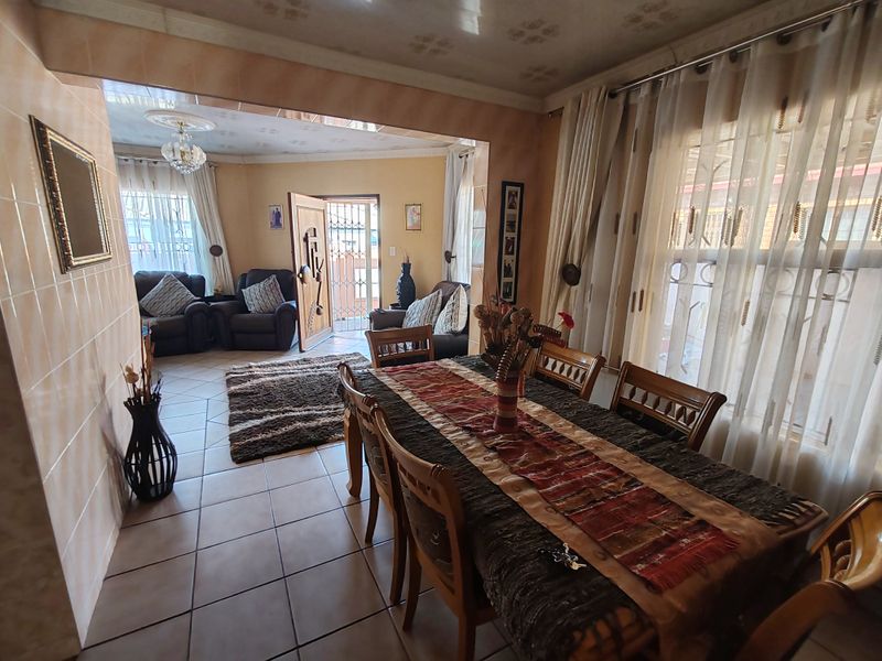 Open plan living and dining area featuring tiled flooring, decorative ceiling details, and direct access to the exterior through a security gate.