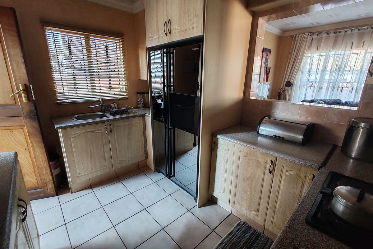 A functional kitchen featuring laminate cabinetry, granite countertops, a stainless steel sink, and a built-in gas hob with ceramic tiled flooring.