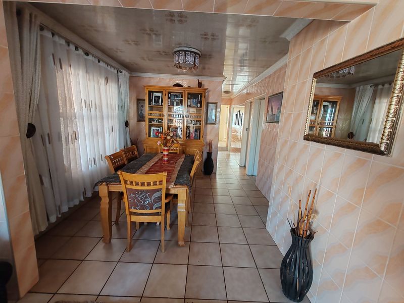 Dining area featuring floor-to-ceiling wall tiles and tiled flooring, offering a dated aesthetic ready for modern updates.