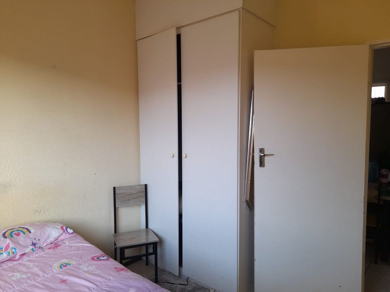 A bedroom featuring a built-in wardrobe with white cabinetry and standard interior door access.