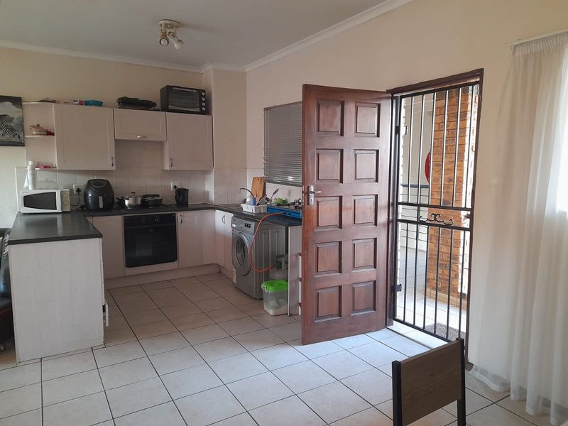 Functional kitchen featuring built-in cabinetry, oven, hob, and tiled flooring, with direct access to an outdoor area through a security gate.