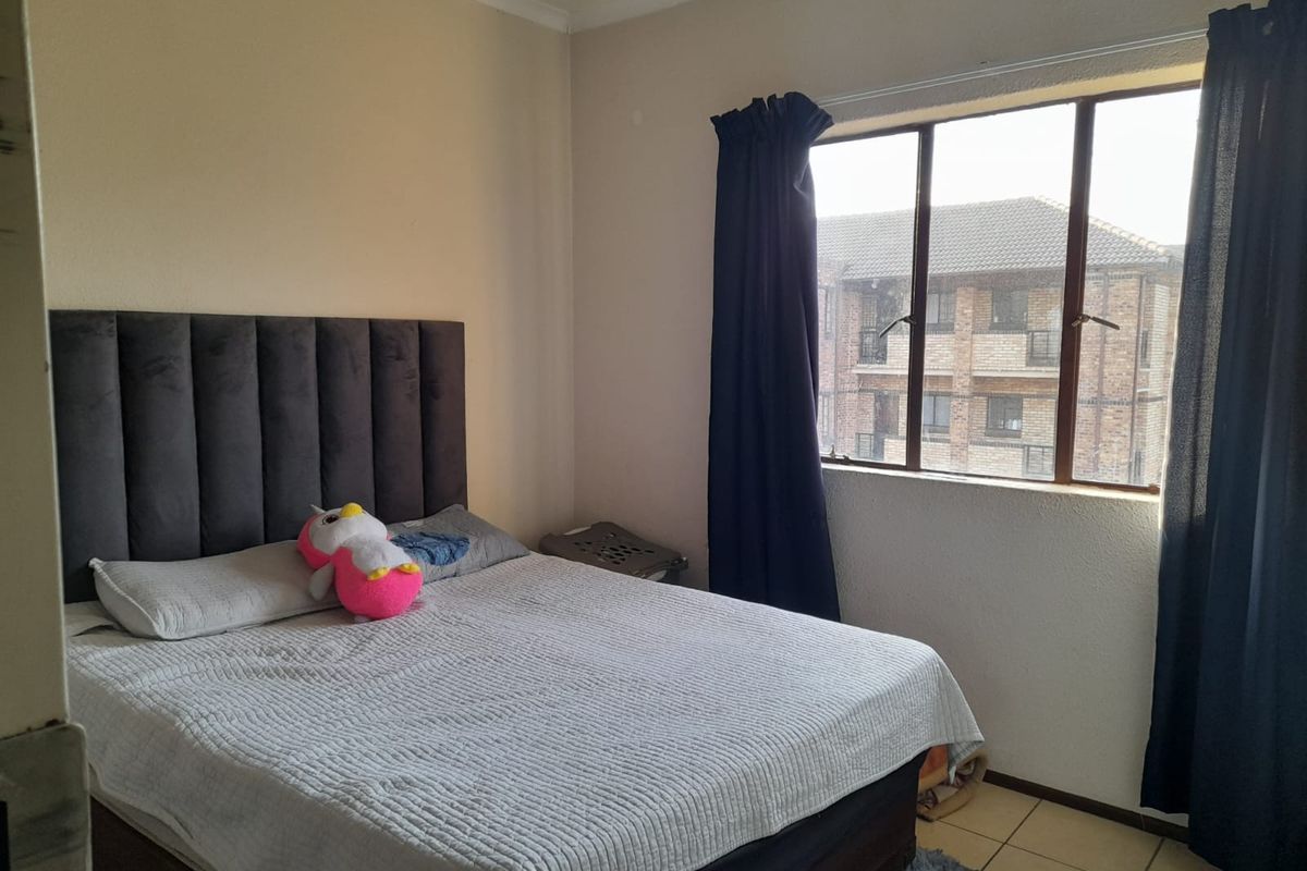 A functional bedroom featuring tiled flooring and a window with views of the surrounding apartment complex.