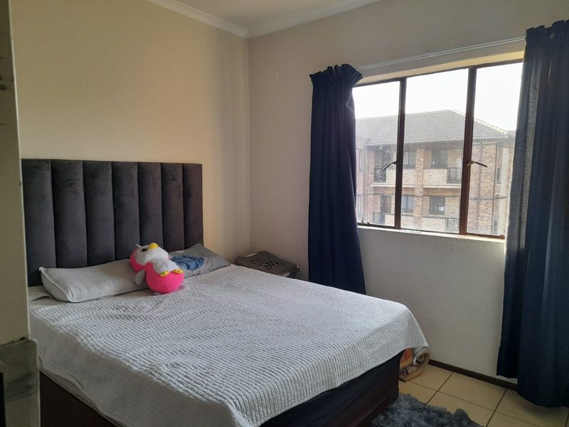 A functional bedroom featuring tiled flooring and a window with views of the surrounding apartment complex.