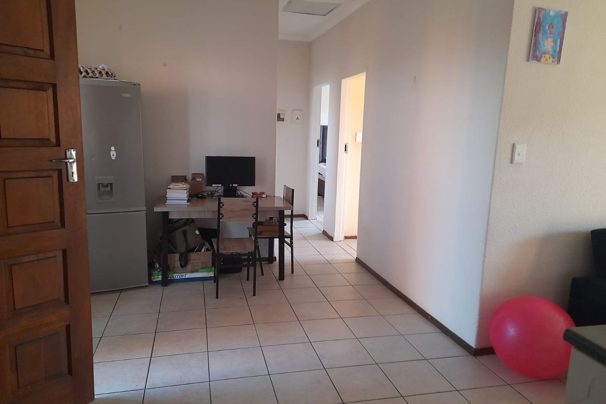 A functional living area featuring neutral tiled flooring and access to adjacent rooms, providing a blank canvas for potential interior updates.