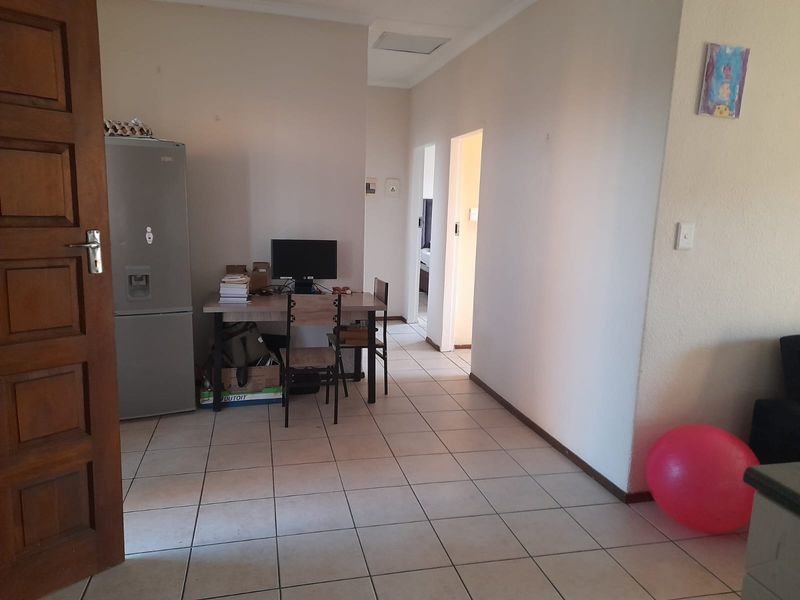 A functional living area featuring neutral tiled flooring and access to adjacent rooms, providing a blank canvas for potential interior updates.
