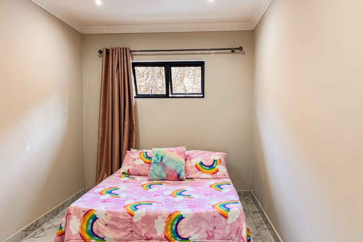A compact bedroom featuring tiled flooring, recessed downlighting, and crown molding, providing a neutral base for interior design.