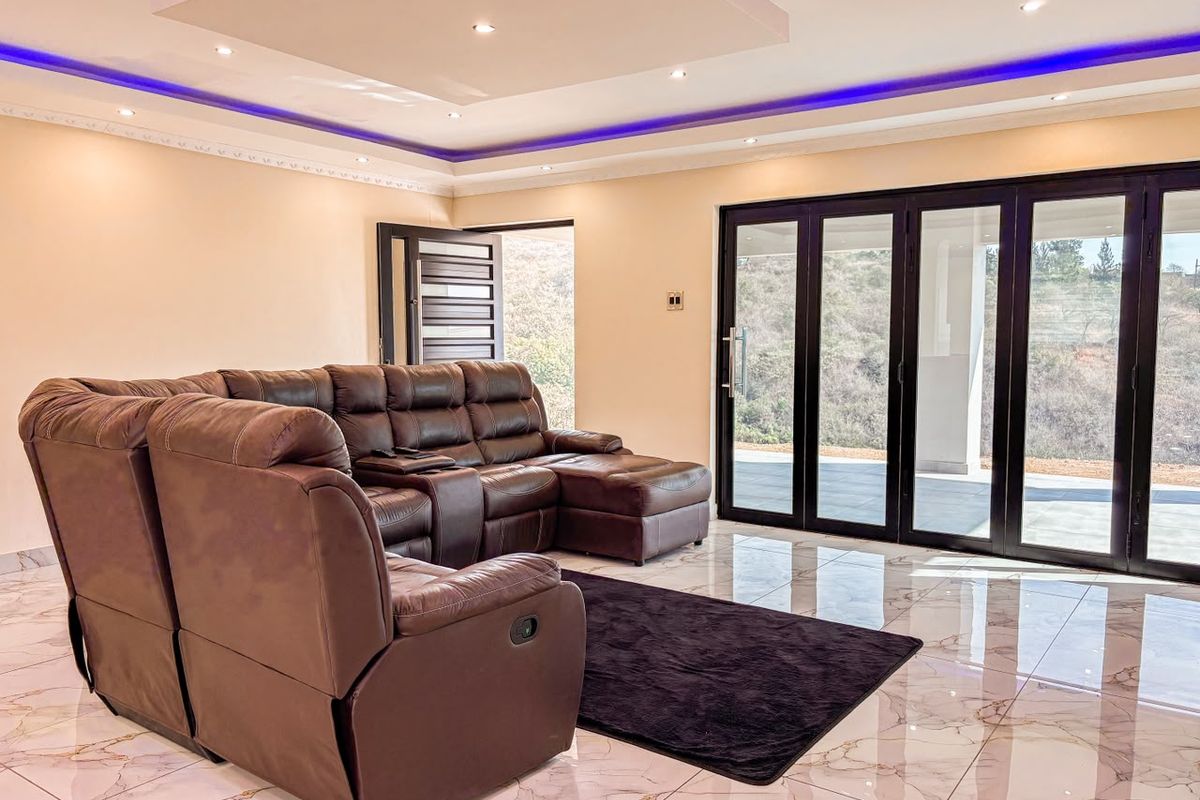 Spacious living room featuring marble-look tiled flooring, recessed ceiling with ambient LED lighting, and large black bifold doors opening to the exterior.