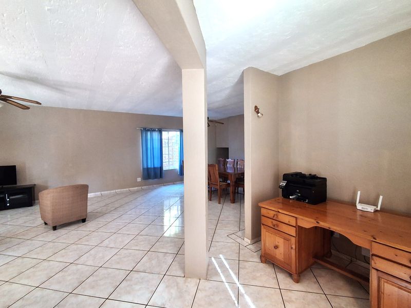 Spacious open-plan living and dining area featuring neutral wall tones and tiled flooring throughout, providing a versatile layout for family living.
