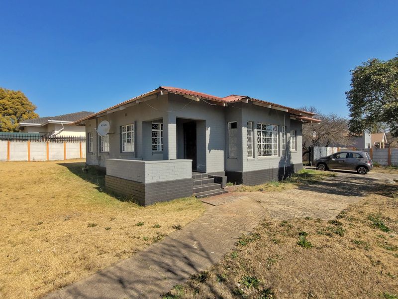 A detached single-story house featuring a tiled roof, brick exterior, and a paved driveway, set on a spacious plot with a boundary wall.
