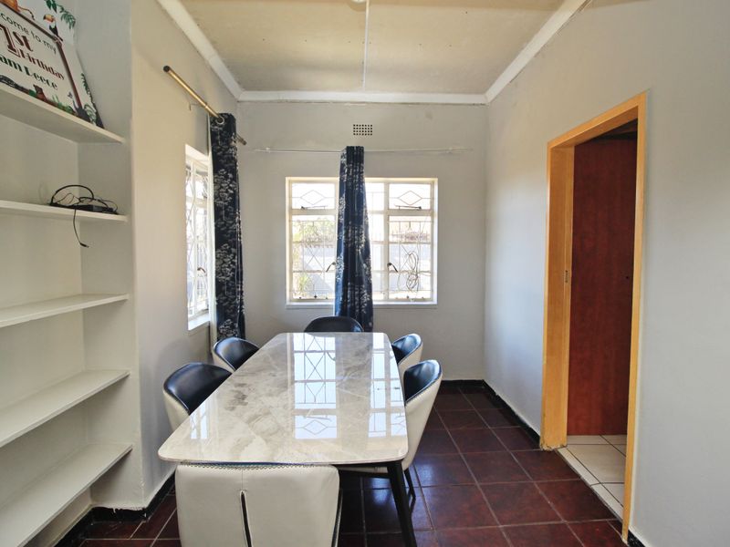 Dining room featuring tiled flooring, built-in shelving, and natural light through windows with security bars.