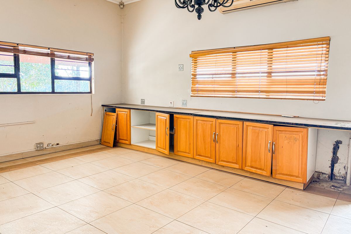 An empty living area featuring tiled floors, built-in wooden cabinetry, and a split-system air conditioner, requiring minor repairs and cosmetic updates.