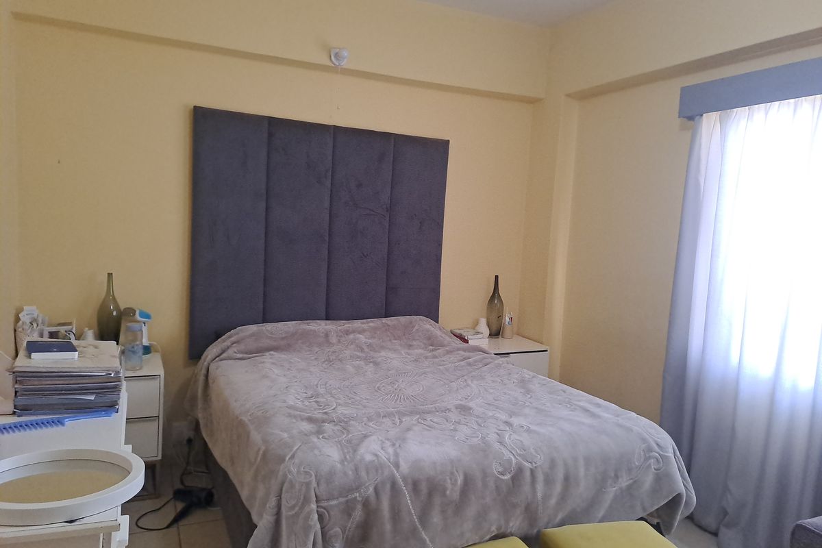 A functional bedroom featuring tiled flooring and a curtain pelmet, providing a neutral base for personalization.